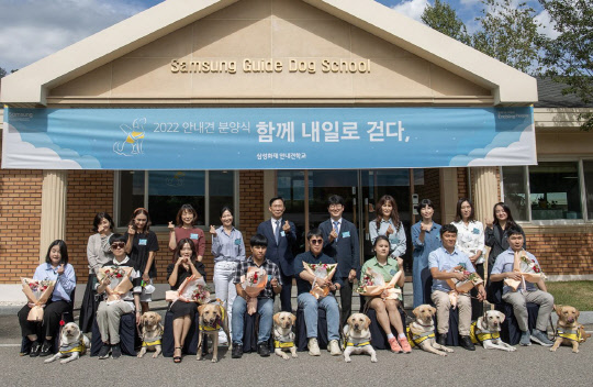 20일 용인 삼성화재안내견학교에서 시각장애인 파트너와 안내견 활동을 시작하는 안내견, 퍼피워커(자원봉사자), 안내견학교 관계자들이 기념 촬영을 하고 있다. <삼성 제공>